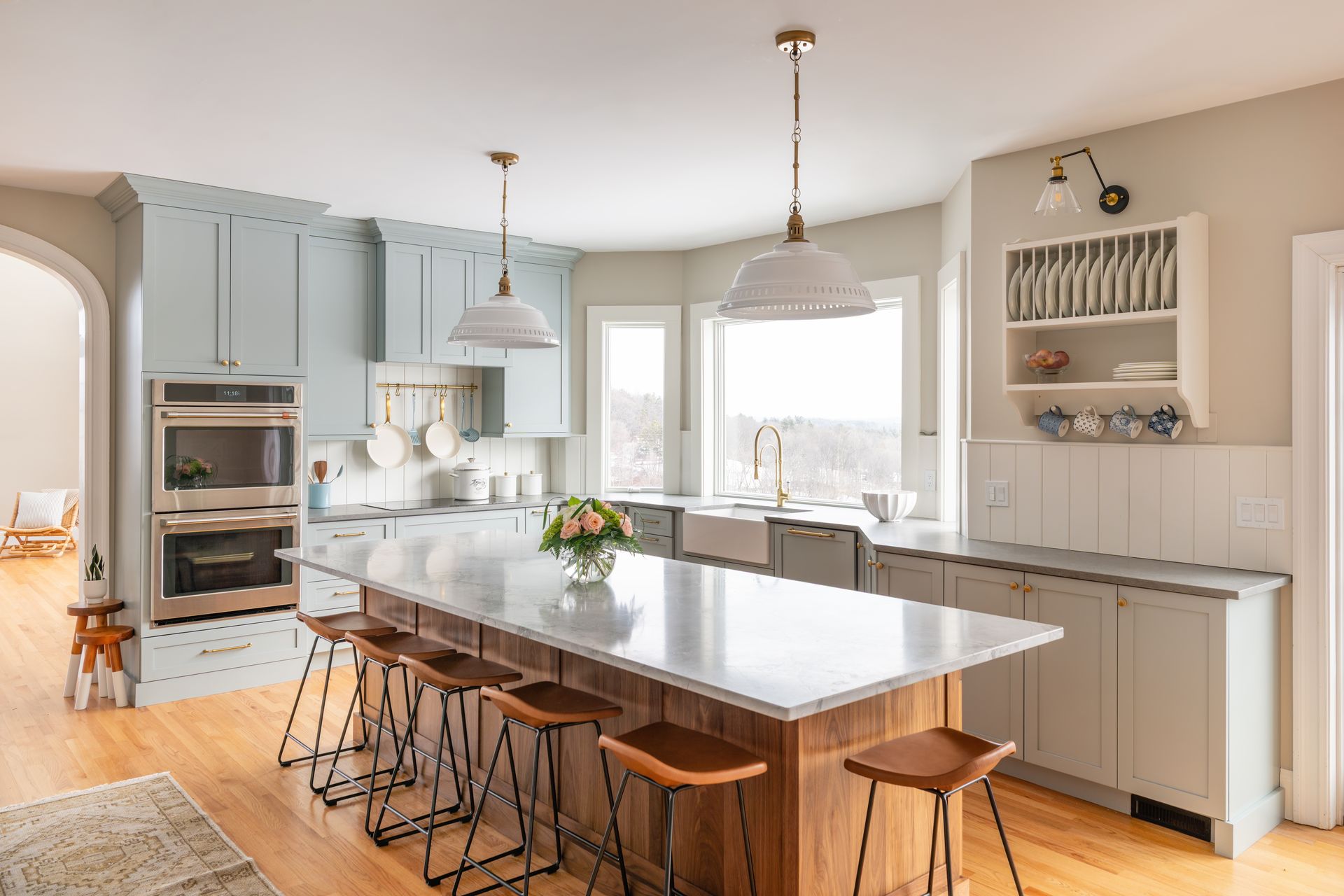 Bright modern kitchen with large island, wooden stools, white cabinets, and pendant lights