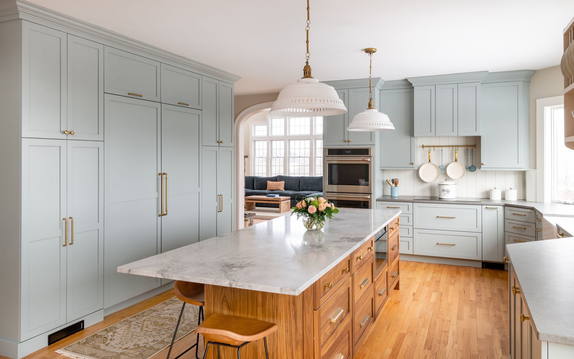 Bright kitchen with light blue cabinets, wood island, marble countertops, and pendant lights