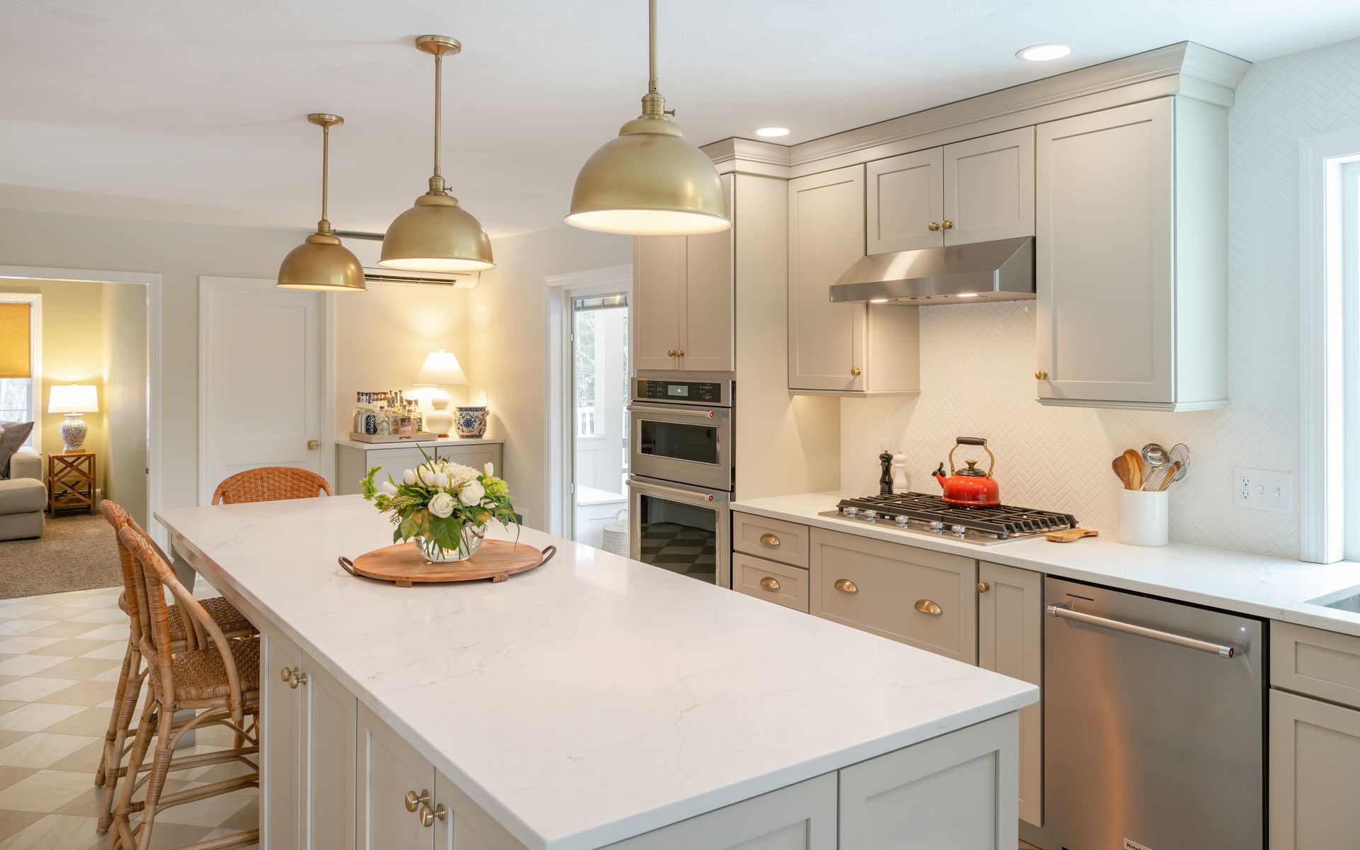 Bright white kitchen with a long island, pendant lights, and stainless appliances in a modern home