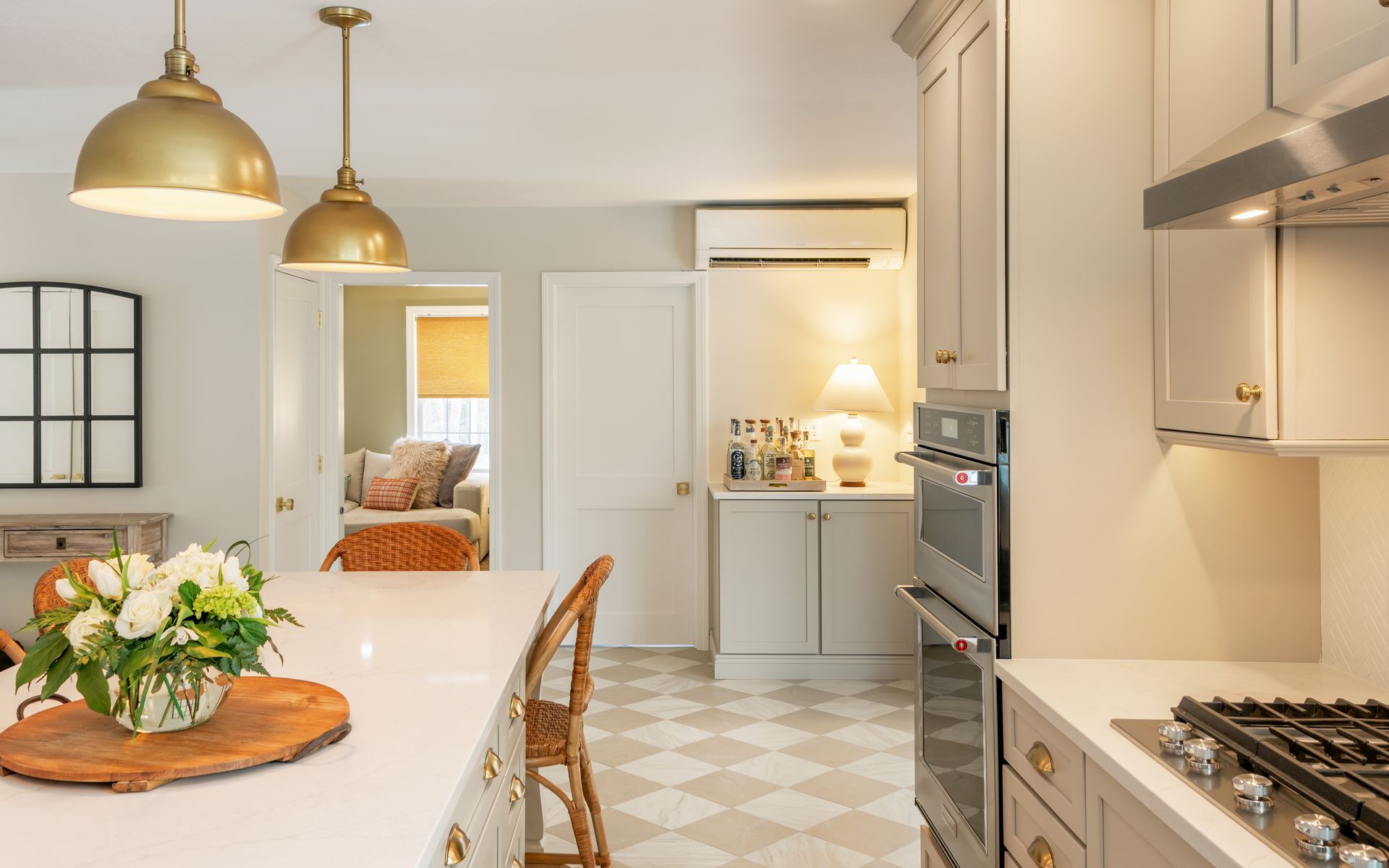 Bright modern kitchen with white cabinets, pendant lights, and a dining table with flowers