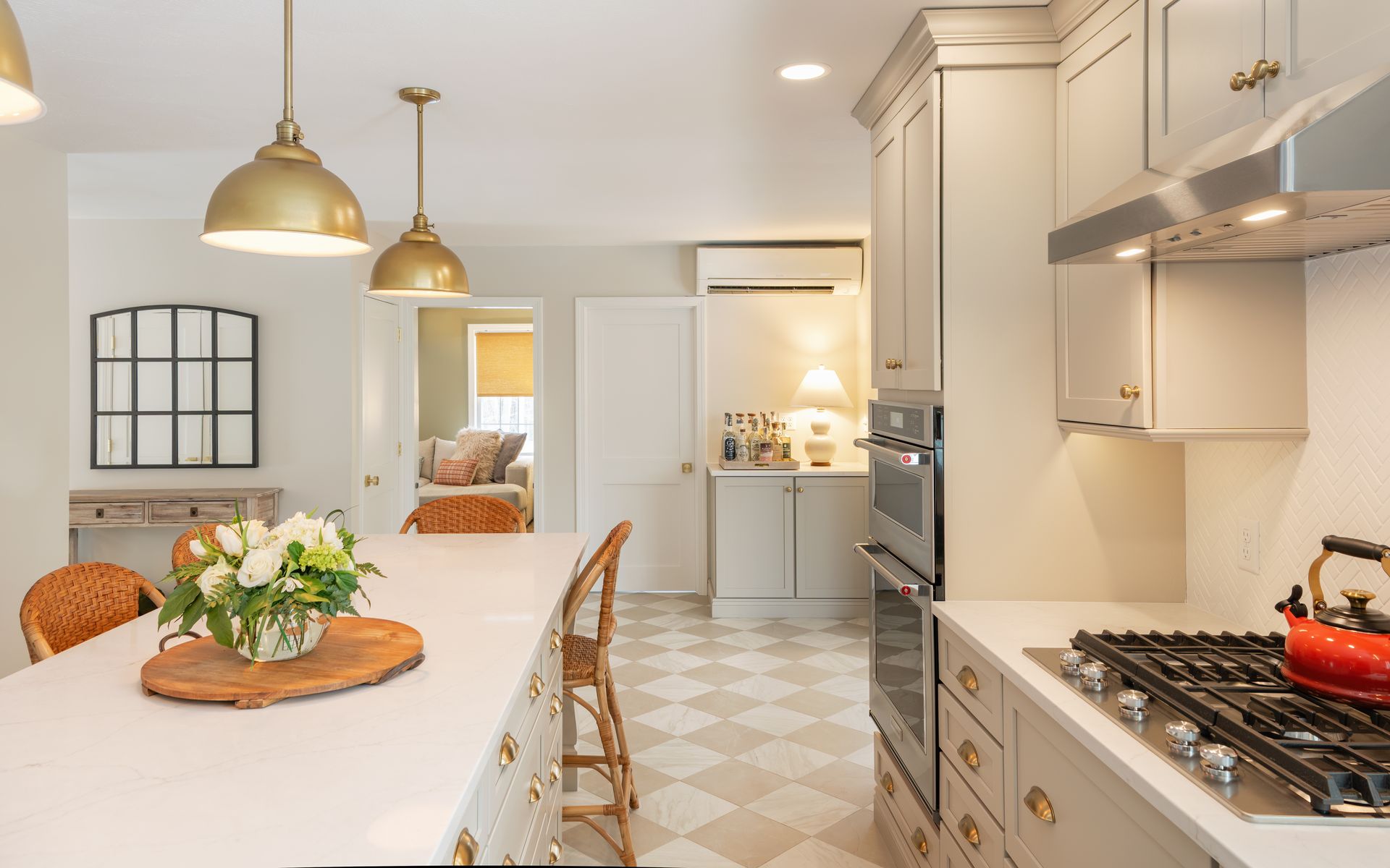 Bright white kitchen with island, pendant lights, and a gas range beside a dining table.
