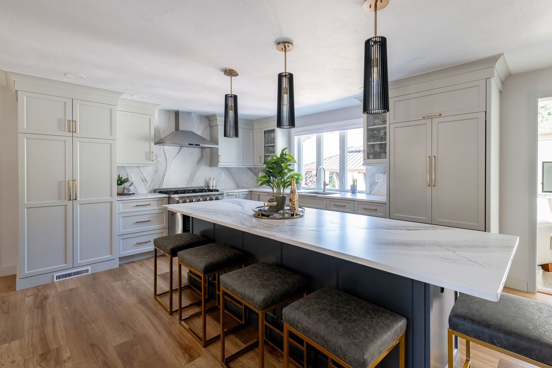 Modern white kitchen with large island, pendant lights, and dark bar stools