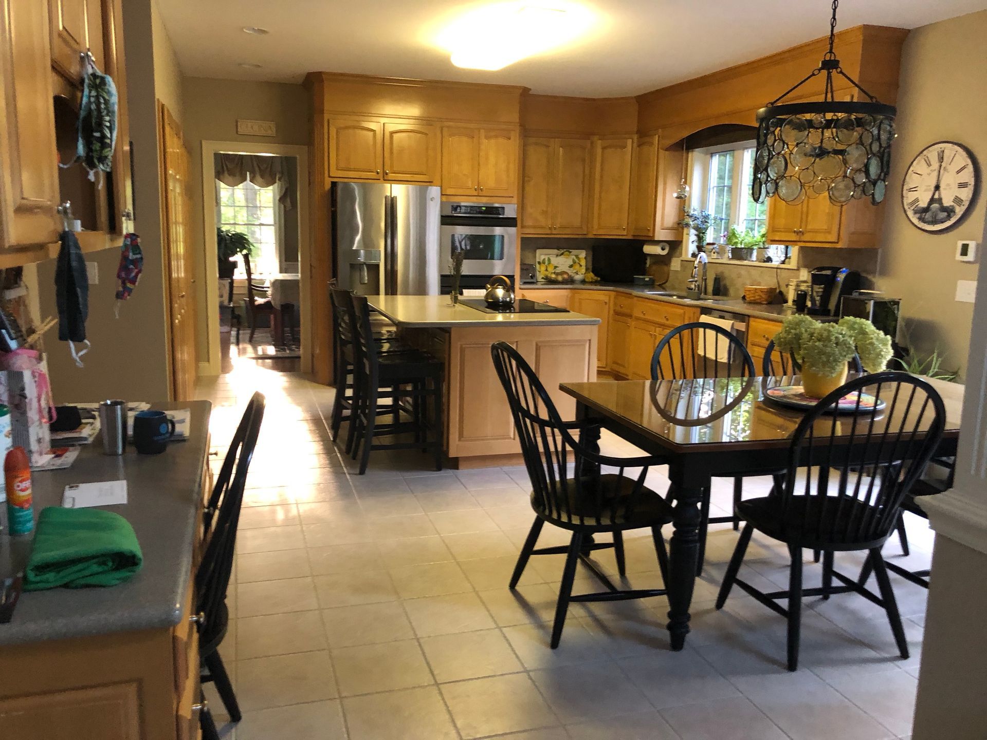 Sunlit kitchen and dining area with wooden cabinets, stainless fridge, and a round table with chairs