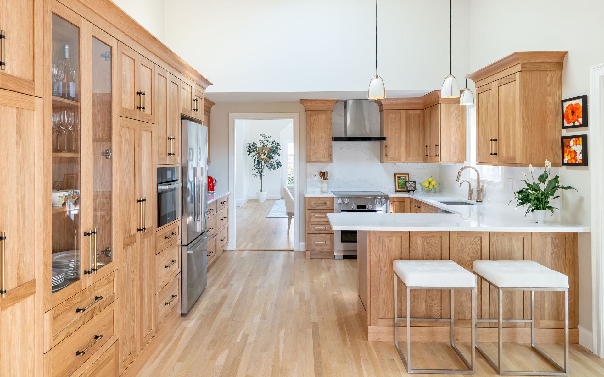 Bright modern kitchen with light wood cabinets, island stools, and stainless steel appliances