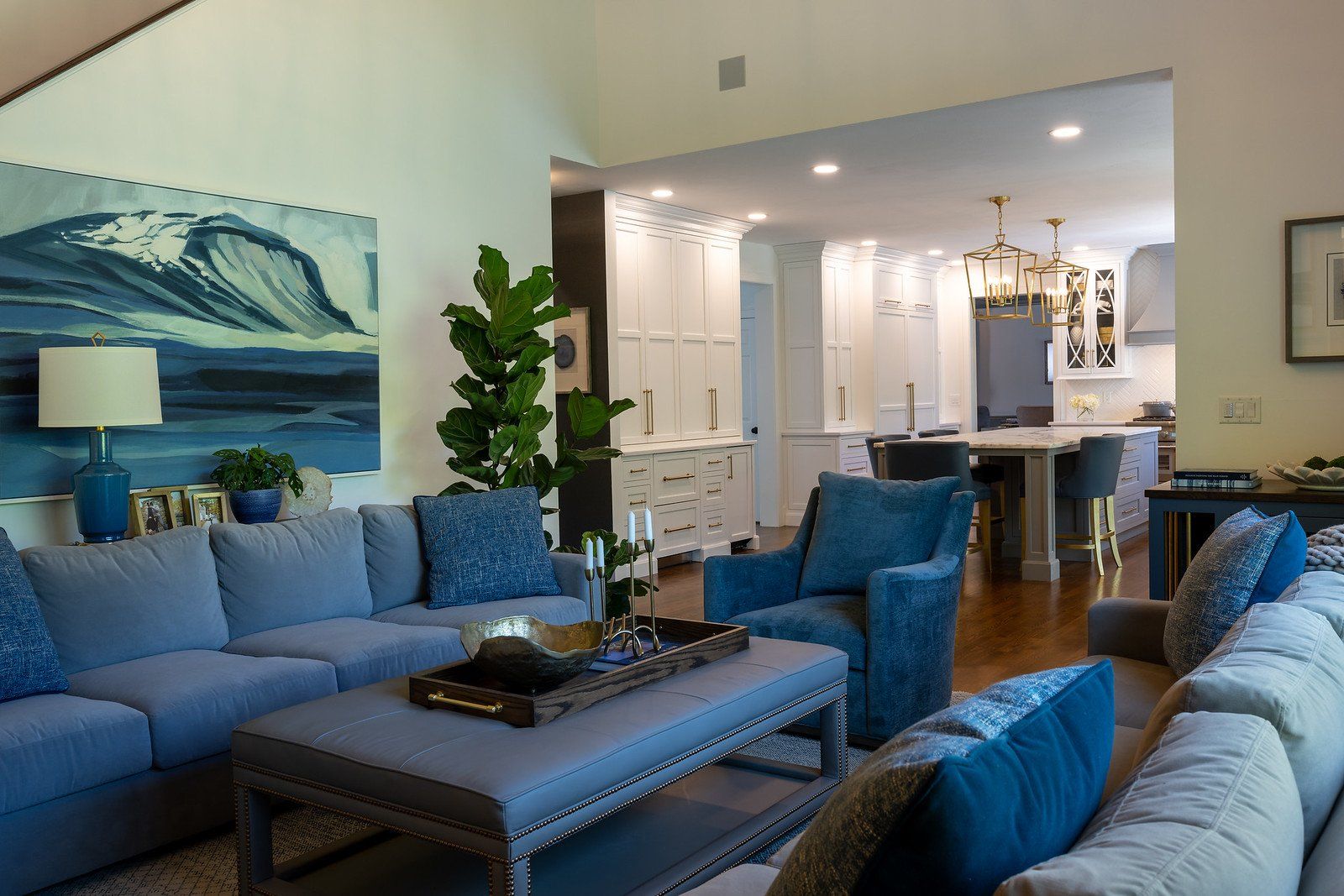 Modern living room with blue sofas, a coffee table, and a kitchen in the background