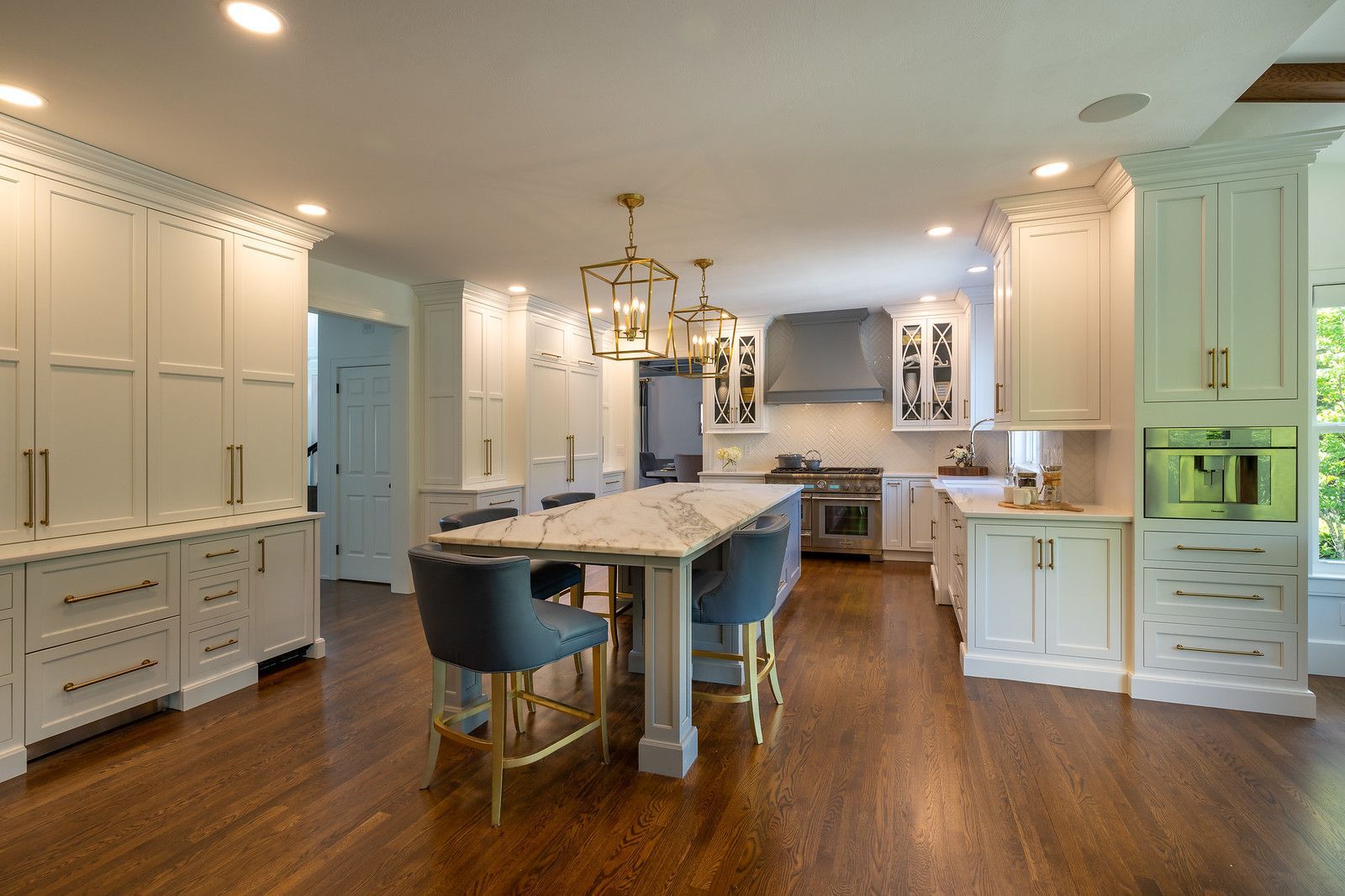Bright, modern kitchen with white cabinets, island, blue stools, and hardwood floors