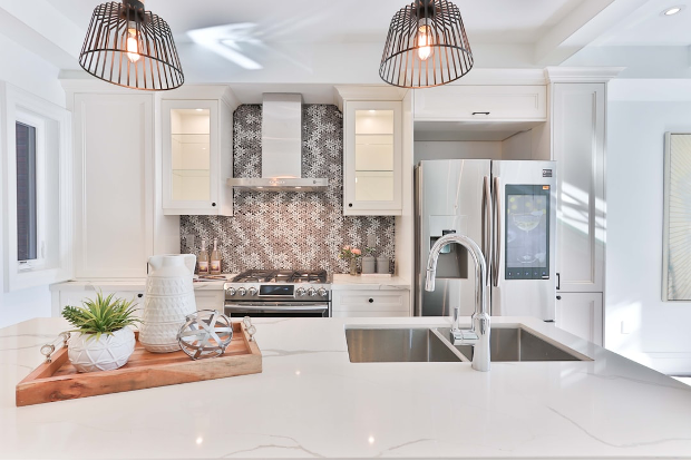 Bright modern white kitchen with island, pendant lights, stainless steel appliances, and tiled backsplash