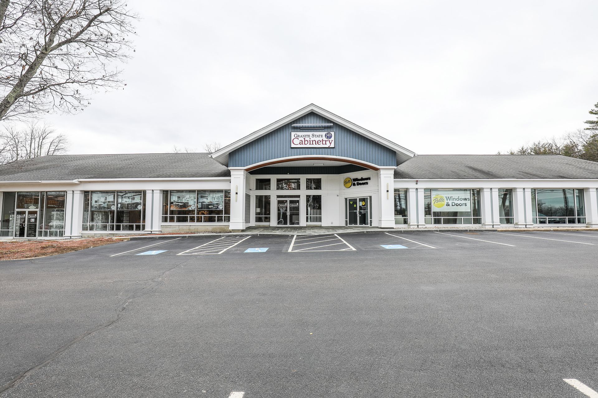 Front view of a small storefront shopping plaza with parking lot and central entrance