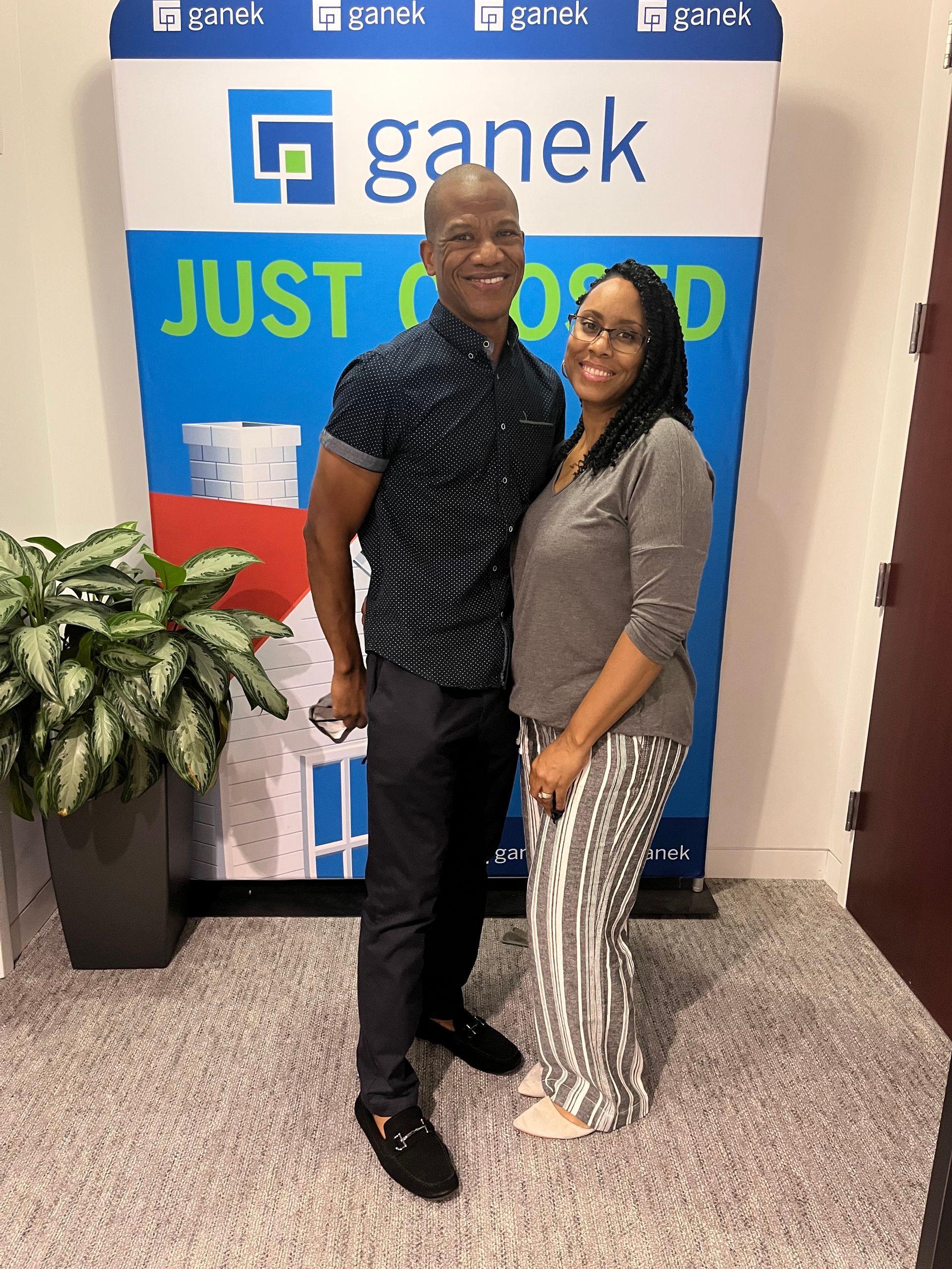 Man and woman standing in front of a “JUST CLOSED” backdrop. Both are smiling.
