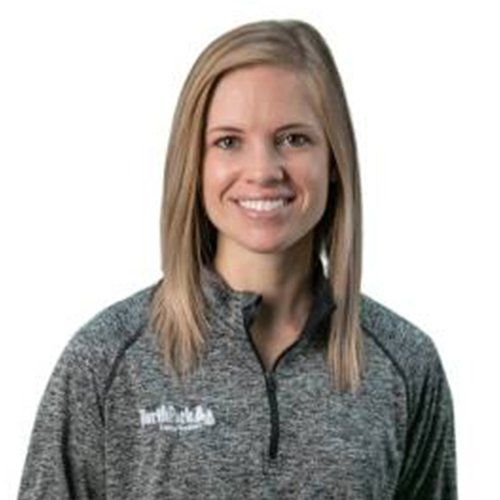 A woman is wearing a gray shirt and smiling.