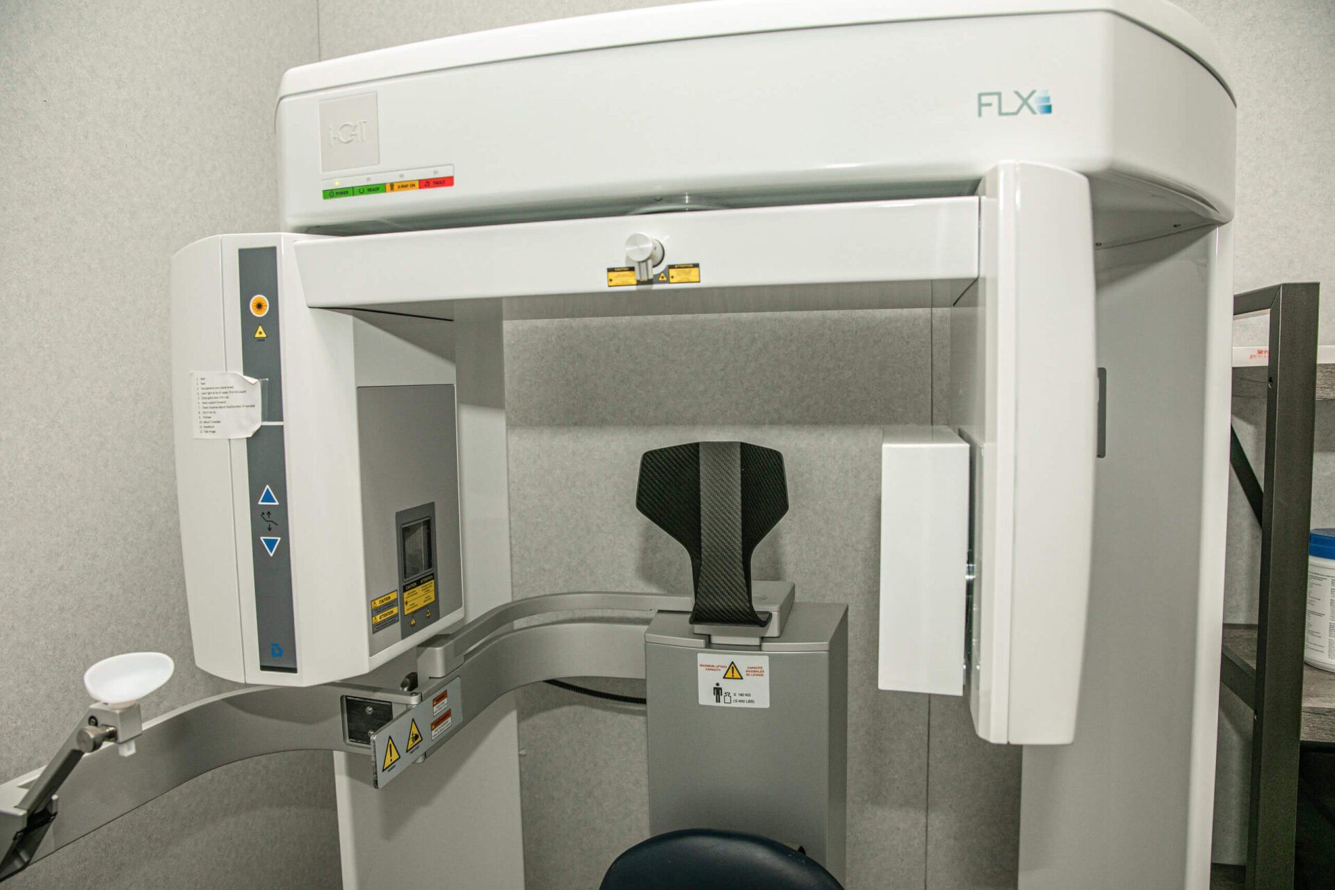 An x-ray machine is sitting in a room next to a chair.