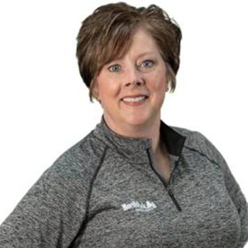 A woman is wearing a gray shirt and smiling for the camera.