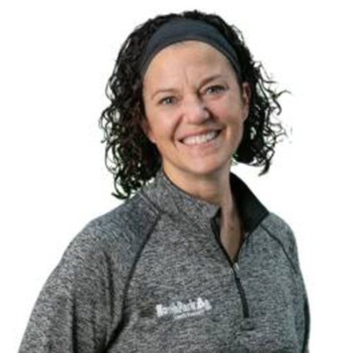 A woman wearing a headband and a gray shirt is smiling.