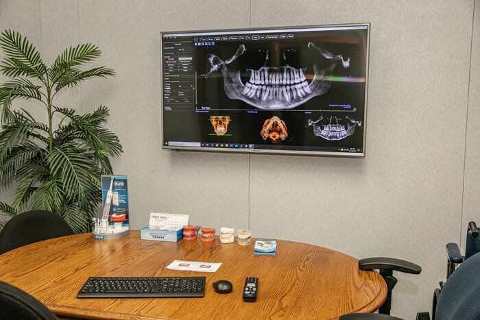 A conference room with a table and chairs and a flat screen tv on the wall.