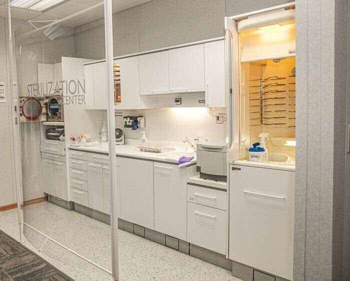 A kitchen in a dental office with white cabinets and appliances.