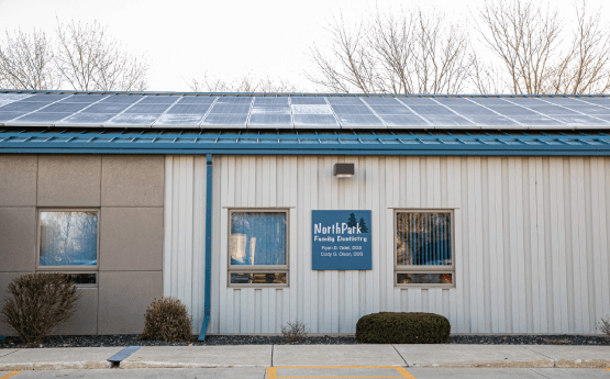 A white building with a blue roof and solar panels on the roof.