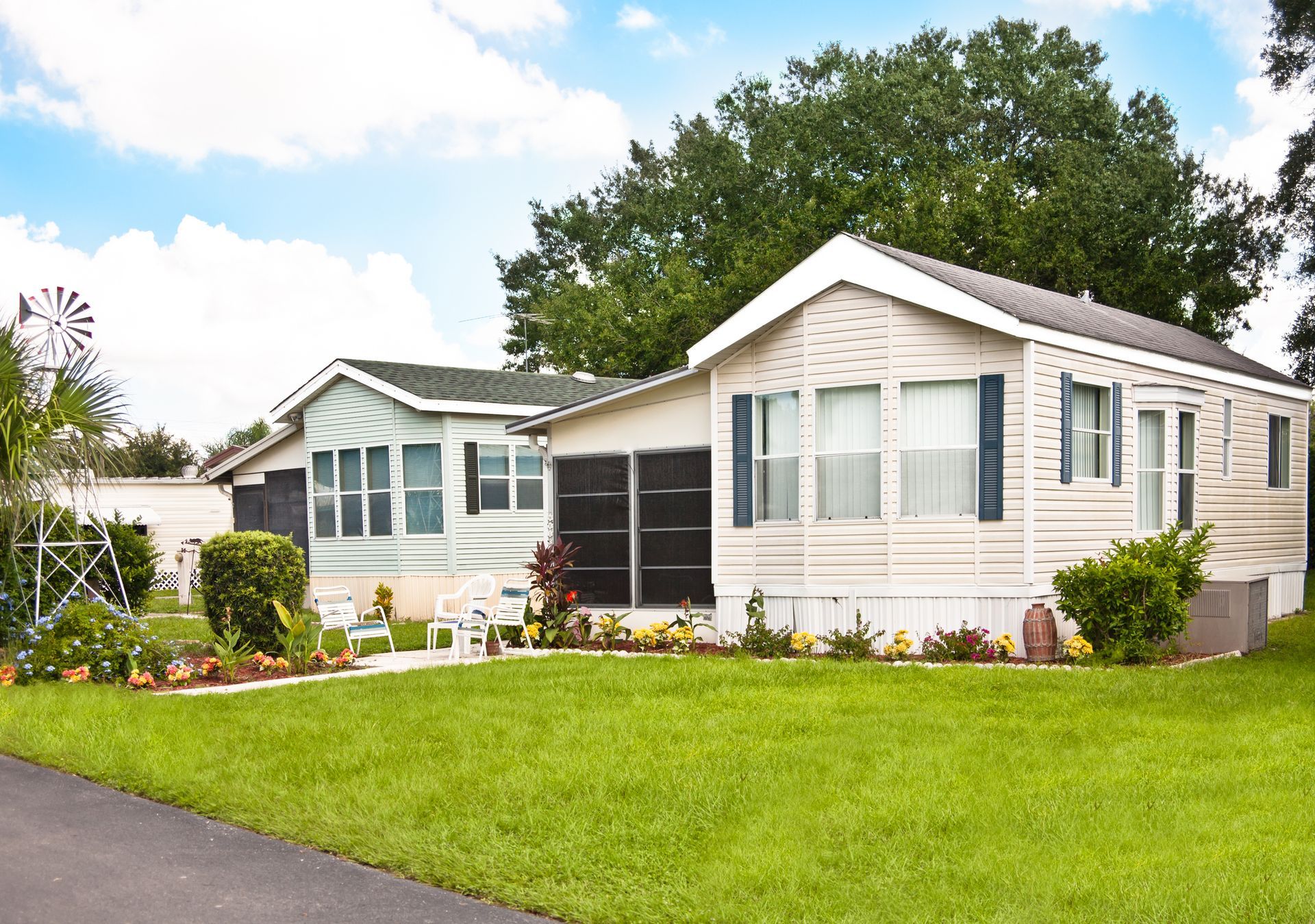 Two mobile homes are sitting next to each other on a lush green lawn.