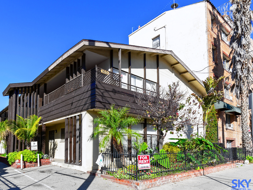 A modern two-story apartment with balconies, palm trees, and a