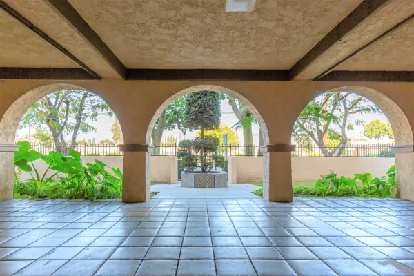 image of a covered deck with curved arch columns in tiles and recessed ceiling leading to the courtyard garden