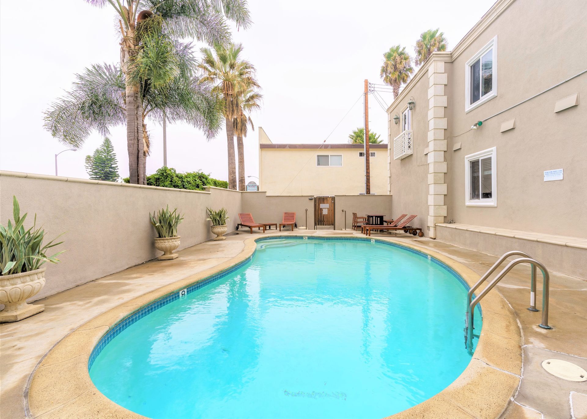 A large swimming pool with palm trees at the back. Sky Properties Inc. - Premier Property Management Company in Toluca Lake