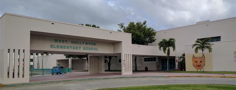 The West Hollywood Elementary School with a covered walkway, palm trees, and a cat mascot mural on the building exterior.
