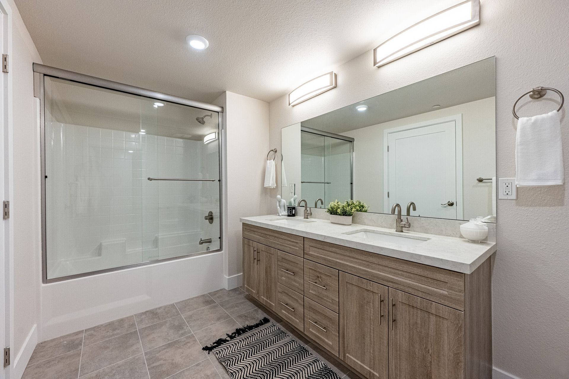 Full bathroom with tub/shower combo and a sleek vanity and large mirror in a unit at The Secret at K-Town
