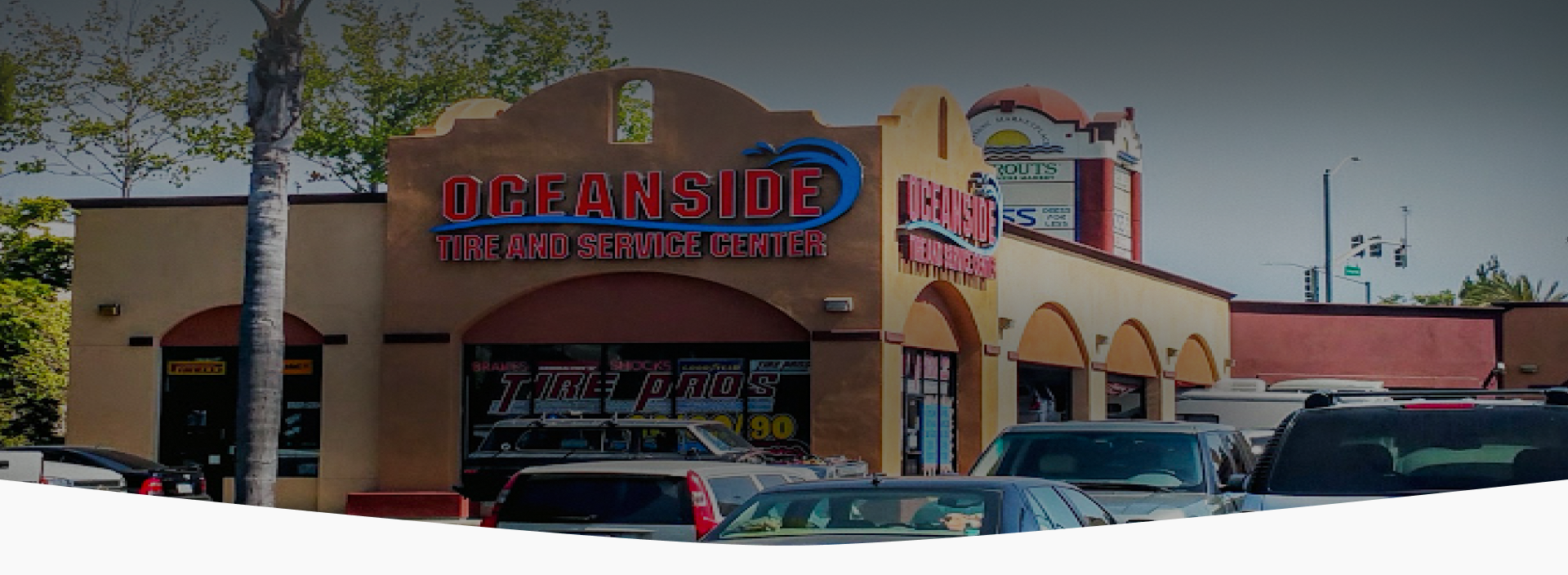 A large building with a lot of cars parked in front of it. | Oceanside Tire and Service Center Tire Pros