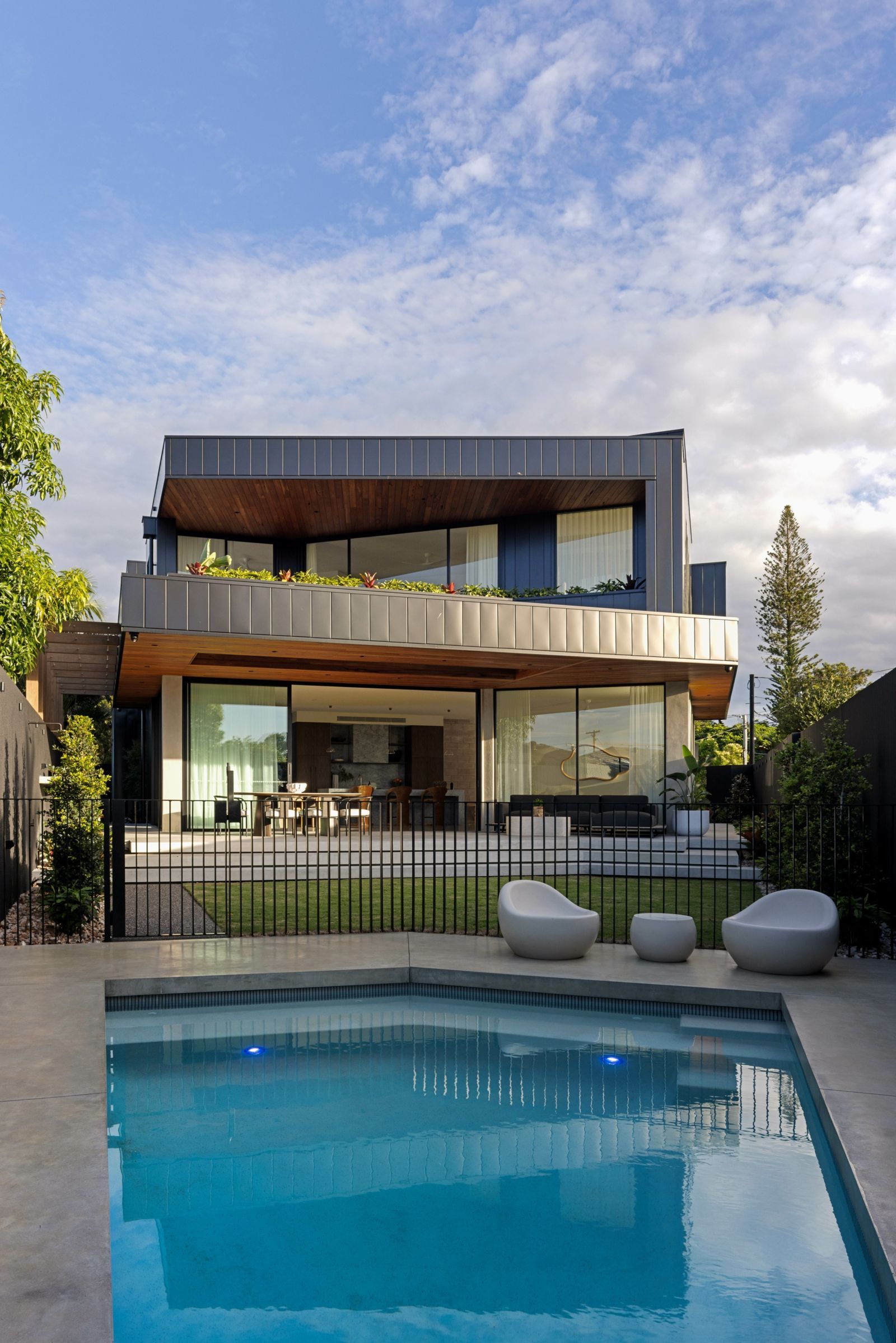 Modern two-story house with a backyard pool and patio at dusk