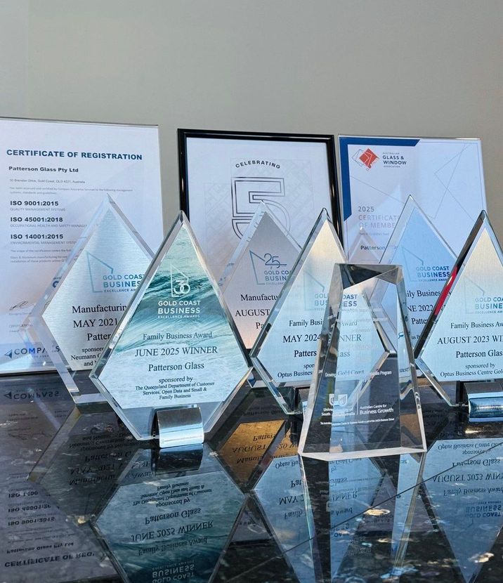Crystal awards and certificates arranged on a reflective surface.
