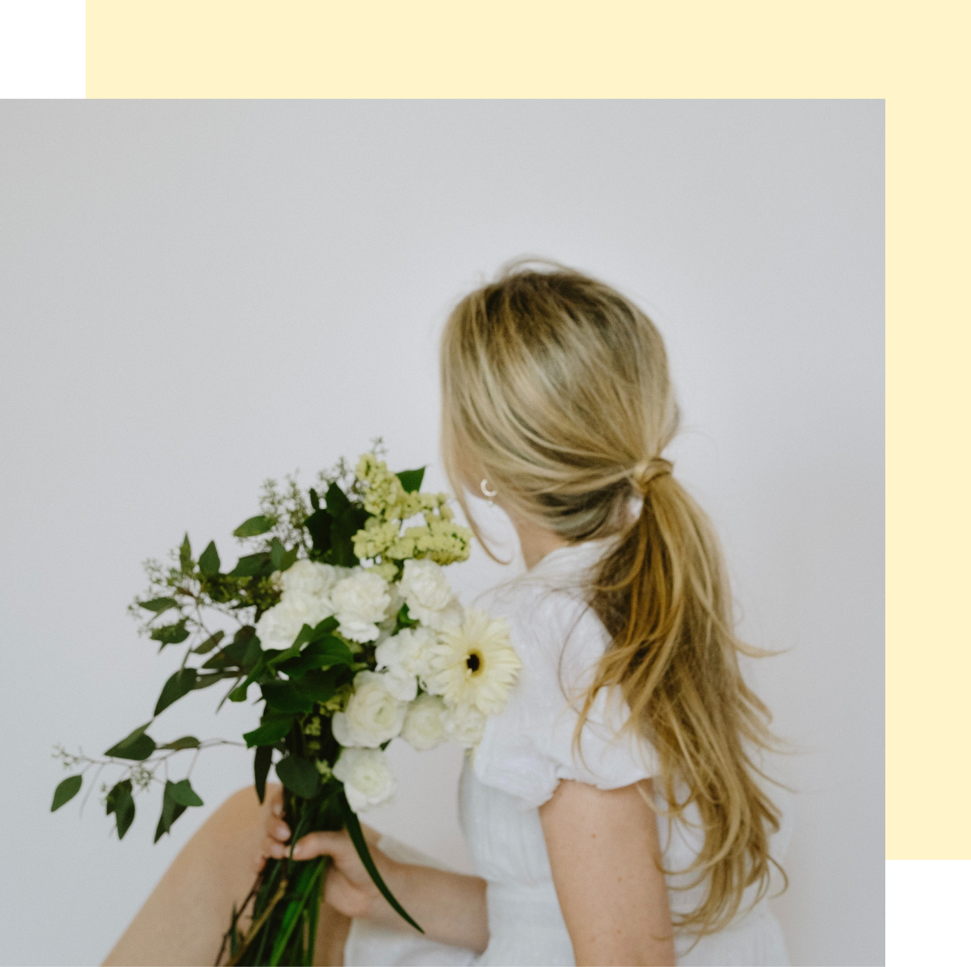 Une femme en robe blanche tient un bouquet de fleurs blanches