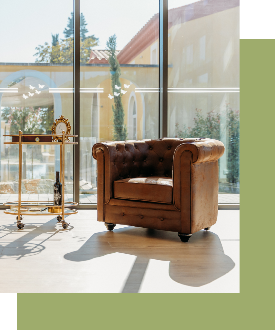 Une chaise en cuir marron est assise devant une grande fenêtre.