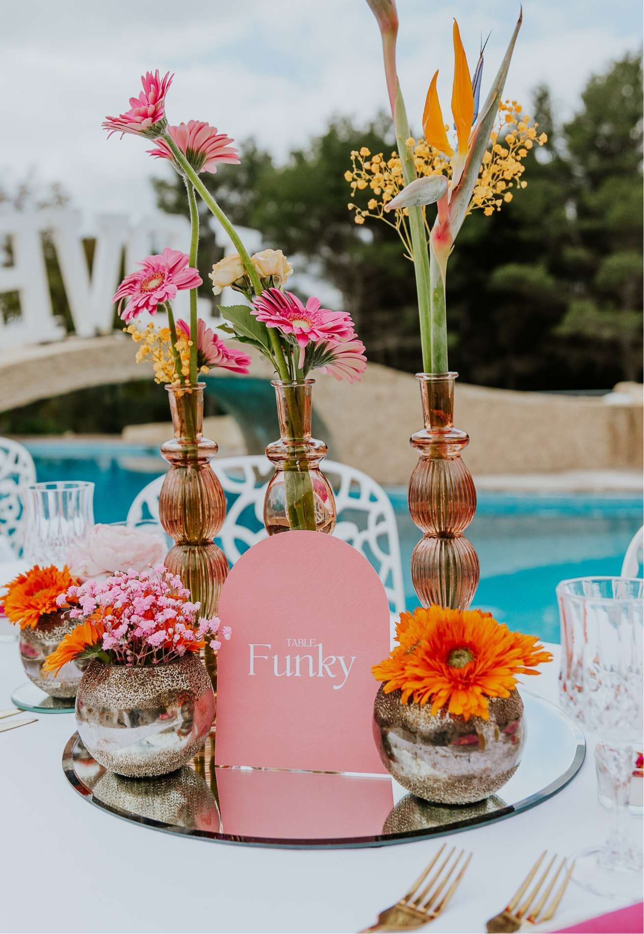 Une table dressée pour une réception de mariage avec des fleurs dans des vases dessus.