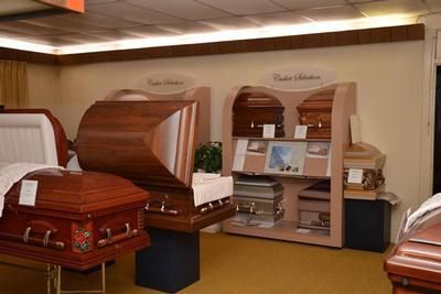 Funeral home showroom with several polished wooden coffins on display in rows