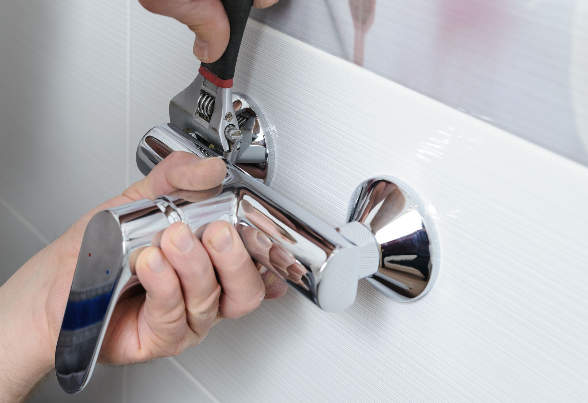 A person is fixing a shower head with a wrench. A person is fixing a shower head with a wrench.