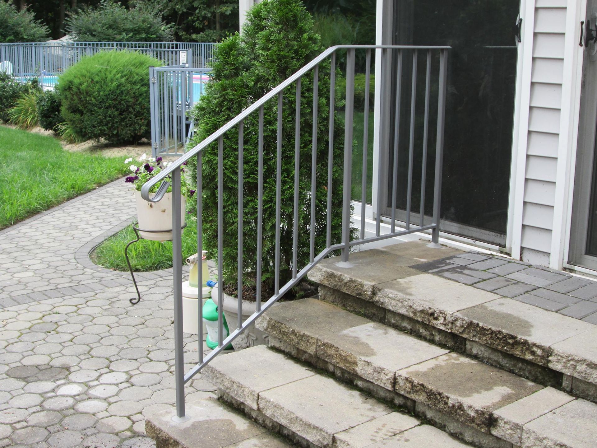 Man installing deck railing post on a staircase. Brown deck and stairs. Gray railing post.