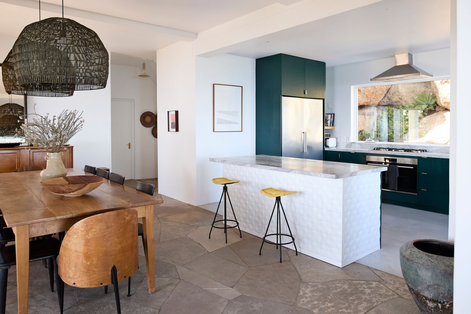 Dining room with wood table and chairs, and kitchen with green cabinets and white island.