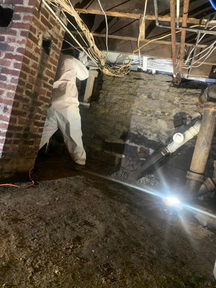 A man is standing in a basement next to a brick wall.