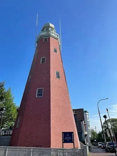 Chimney sweep portland maine- A tall, red brick tower with a light green cap stands against a clear blue sky.