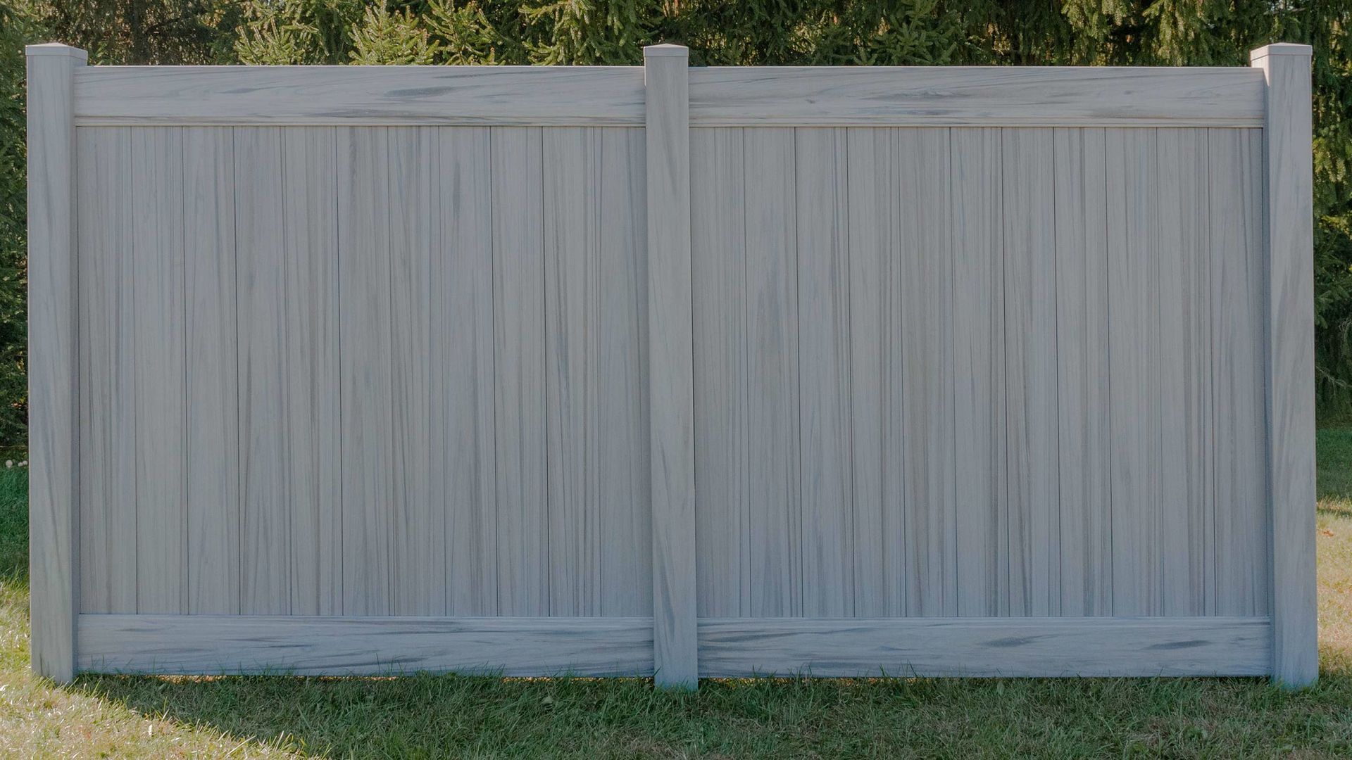 A gray wooden fence is sitting on top of a lush green field.