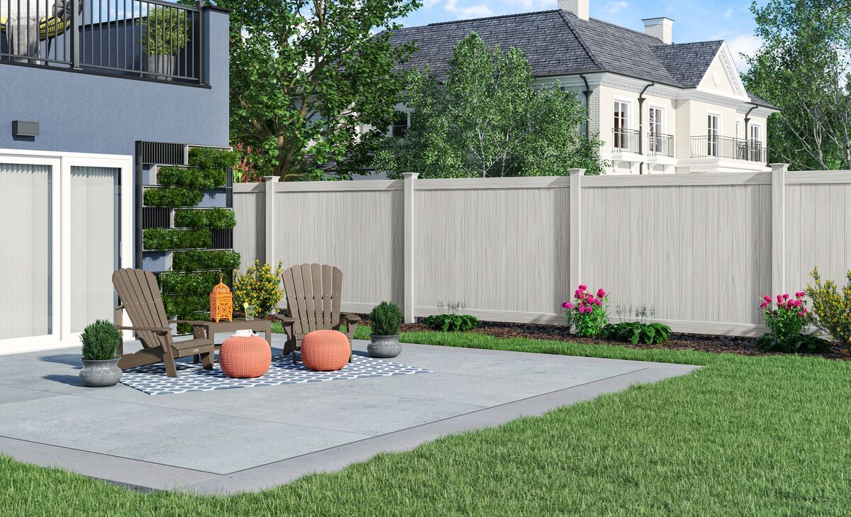 Classic wood grain aspen vinyl privacy fence. There is a patio with chairs and ottomans in the backyard of a house.