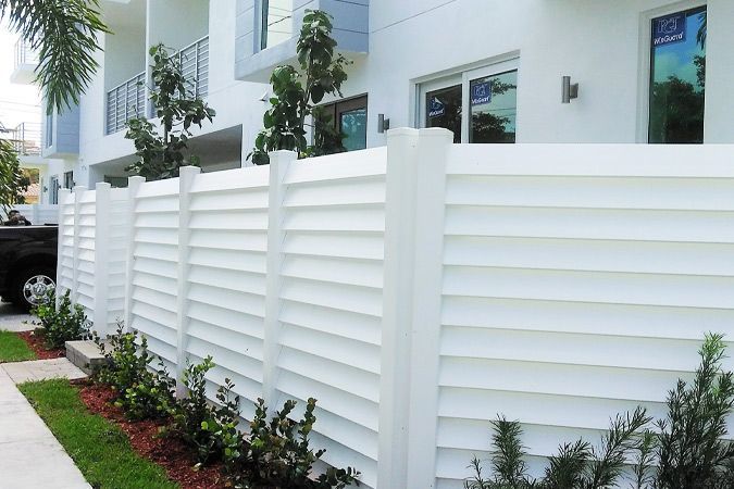 A white fence is in front of a white building.