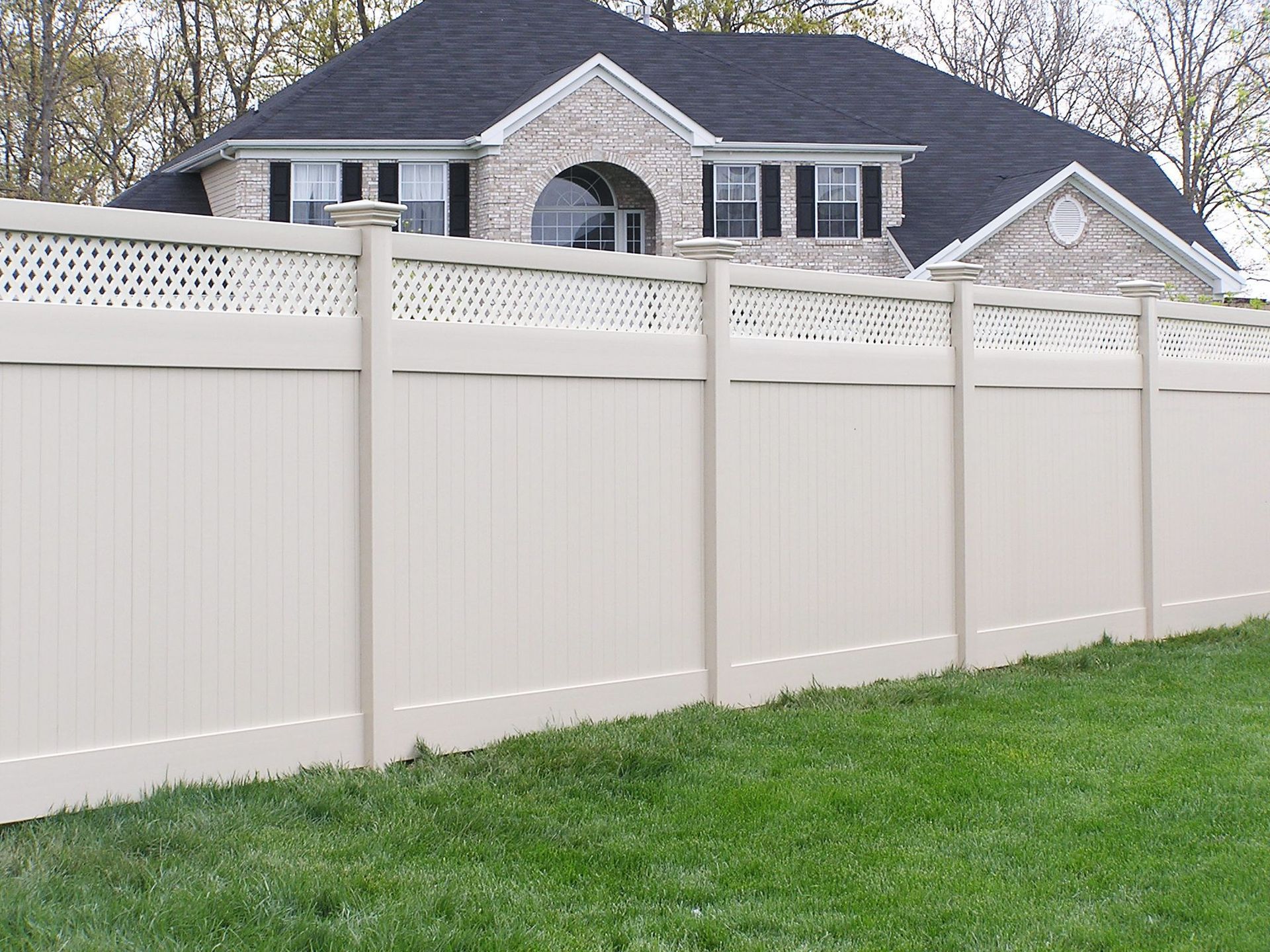 A white fence surrounds a house with a black roof