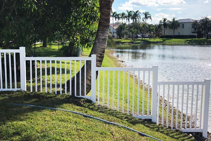 A white fence surrounds a lake in a park.