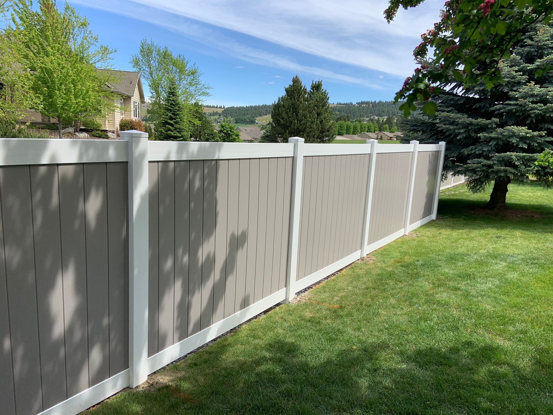 A gray and white fence surrounds a lush green yard.