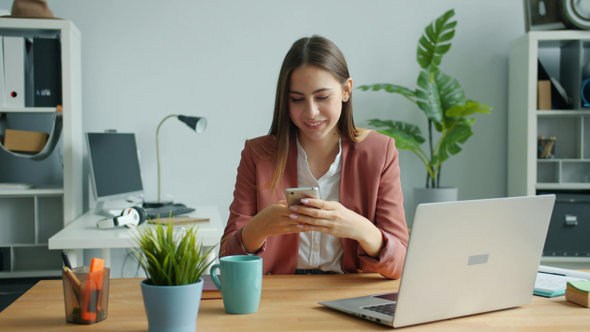 Professional woman checking her phone at a modern desk, representing office space in Colorado Springs for growing businesses.