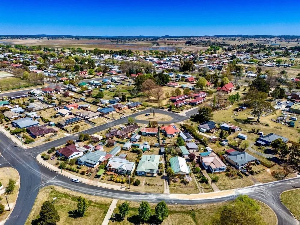 An aerial view of a residential neighborhood with paved streets and scattered homes under a clear blue sky.