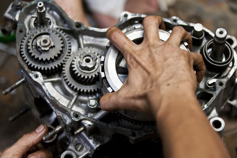Hands Inspecting Exposed Gears and Engine Parts — AA Automotive Repairs in Forster, NSW