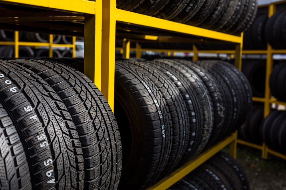 Rows of Black Tires Stacked on Yellow Metal Racks in a Warehouse — AA Automotive Repairs in Forster, NSW