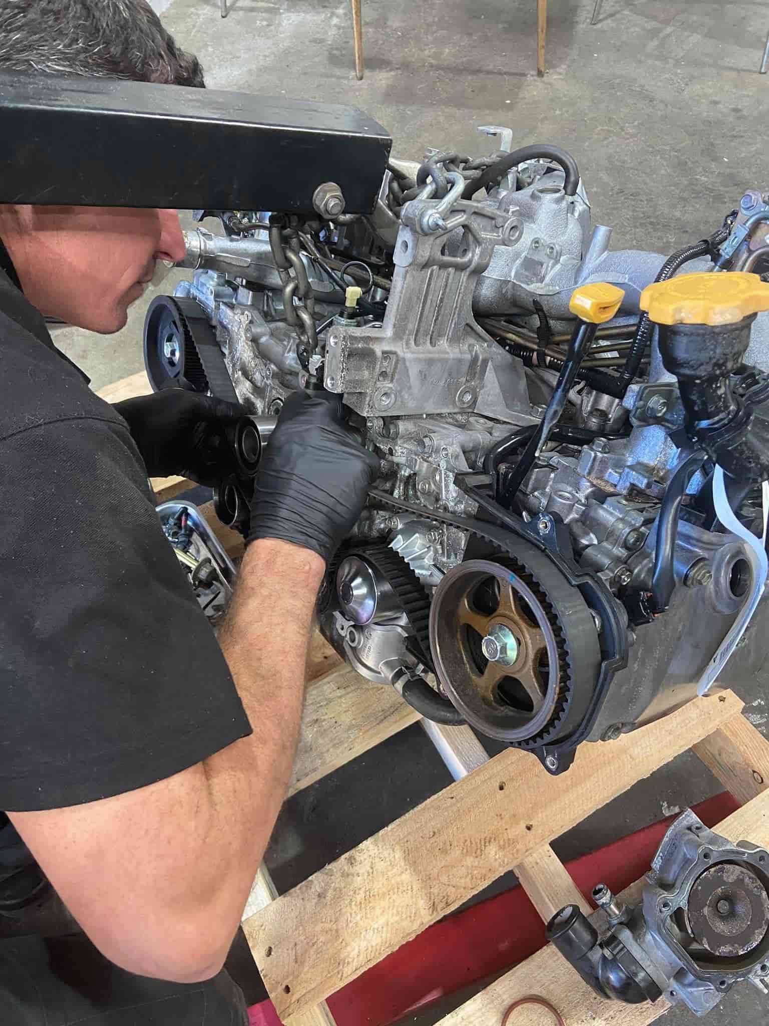 Mechanic Working on a Car Engine Mounted on a Stand in a Workshop — AA Automotive Repairs in Forster, NSW