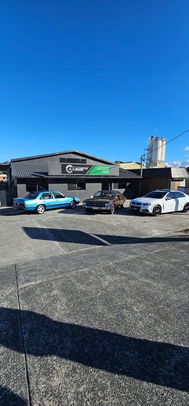 Two Parked Cars Outside a Low Building Under a Bright Blue Sky — AA Automotive Repairs in Forster, NSW